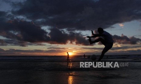 Wisatawan bermain bola di pantai Kuta, Bali.