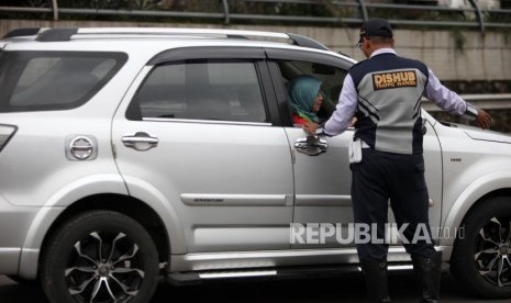 Petugas Dishub mengarahkan kepada pengendaran mobil bernomor polisi ganjil saat hari pertama pemberlakuan sistem ganjil genap di Gerbang Tol Bekasi Barat 1, Bekasi, Jawa Barat, Senin (12/3).