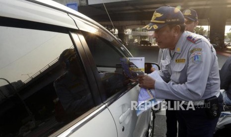 Petugas Dinas Perhubungan DKI Jakarta saat melakukan sosialisasi uji coba perluasan sistem ganjil genap kepada pengendara di kawasan Pramuka, Jakarta, Senin (12/8).