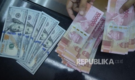 Petugas menghitung mata uang rupiah dan dolar AS di salah satu tempat penukaran uang di Jakarta, Jumat (9/11).