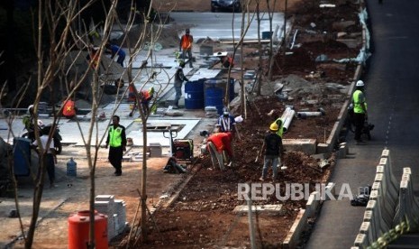 Sejumlah pekerja menyelesaikan proyek pembangunan pedestrian di Jalan Sudirman, Jakarta, Ahad (1/7).