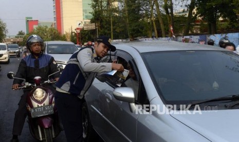 Petugas Dinas Perhubungan DKI Jakarta saat melakukan sosialisasi uji coba perluasan sistem ganjil genap kepada pengendara di kawasan Pramuka, Jakarta, Senin (12/8).