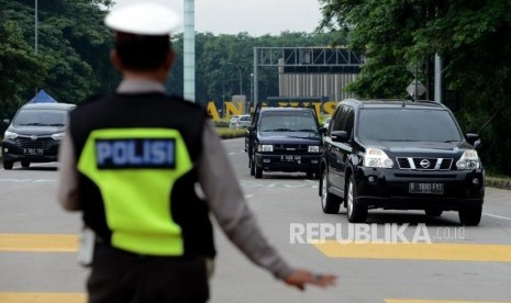 Petugas kepolisian memantau kendaraan roda empat yang melanggar kebijakan ganjil-genap (ilustrasi).