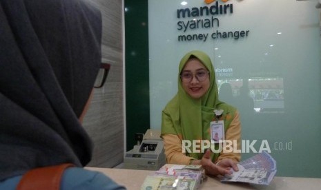 Seorang pegawai Bank Mandiri Syariah melayani nasabahnya saat melakukan penukaran uang Saudi Arabian Riyal (SAR) di Bank Mandiri Syariah Jakarta, Kamis (27/6).