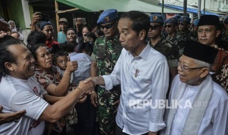 Capres Petahana Joko Widodo (tengah) bersama Cawapres Ma’ruf Amin (kanan) menyapa warga usai pidato kemenangan sebagai Presiden periode 2019-2024 di Kampung deret,Tanah tinggi,Johor baru, Jakarta Pusat, Selasa (21/5).