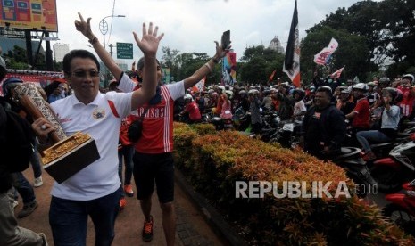 Salah satu pengurus Persija  menyapa para suporter dengan membawa trofi Piala Presiden saat akan melakukan pawai menuju Balaikota di Kawasan Senayan, Jakarta, Ahad (18/2).