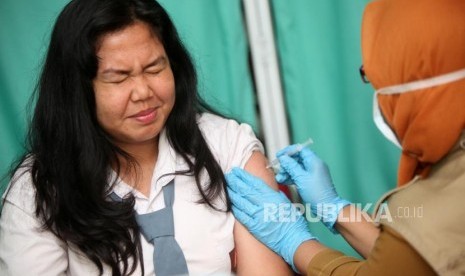 Seorang siswi berekspresi saat diimunisasi difteri pada sosialisasi komitmen pelaksaan kegiatan Outbreak Response Immunization (ORI) Difteri di Sekolah SMAN 33 Jakarta, Jalan Kamal Raya, Jakarta Barat, Senin (11/12).