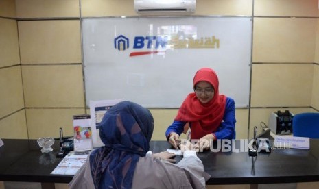 Petugas melayani transaksi nasabah di kantor layanan BTN Syariah, Jakarta, Senin (1/10).