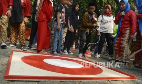 Anak-anak bermain gangsing pada acara Festival Permainan Tradisional Anak Betawi di Hutan Kota Srengseng, Jakarta, Sabtu (3/8).