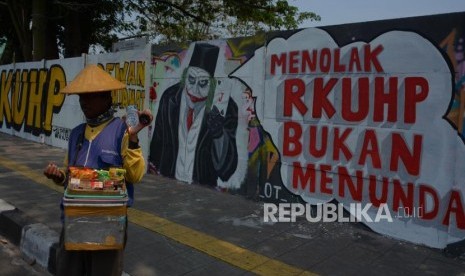 Warga melintas di area mural Tolak RUU RKUHP di Rawamangun, Jakarta Timur. 