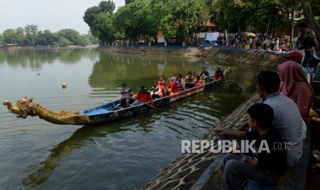 Sejumlah wisatawan saat menaiki perahu naga di Setu Babakan, Jakarta, Ahad (9/6).