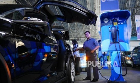 TAKSI LISTRIK. Awak armada e-Taxi Silver Bird memperagakan pengisian baterai mobil Tesla X75 di Port Charging Bluebird di Jakarta, Senin (22/4).