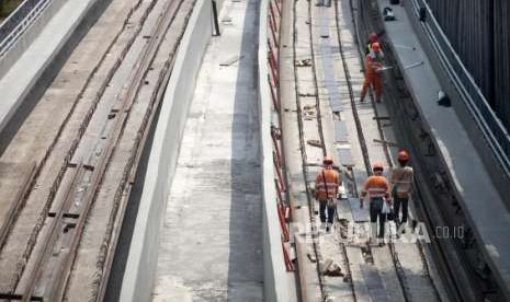 Pekerja berjalan saat menyelesaikan pemasangan rel Kereta Light Rail Transit (LRT) Jabodebek di kawasan Kampung Makassar, Jakarta,  Selasa (28/8).