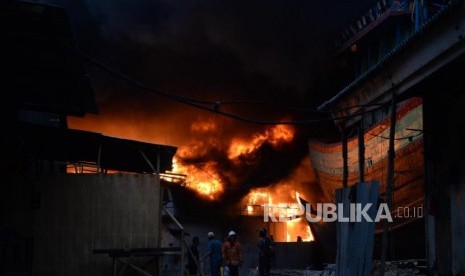 Sejumlah petugas pemadam kebakaran dibantu warga berusaha memadamkan kapal yang terbakar di Pelabuhan Muara Baru, Jakarta, Sabtu (23/2).