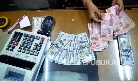 Petugas menghitung mata uang rupiah dan dolar AS di salah satu tempat penukaran uang di Jakarta, Jumat (9/11).