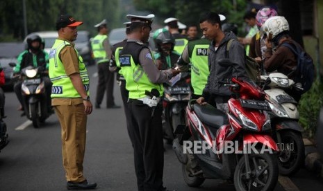 Petugas gabungan melakukan penertiban pajak kendaraan bermotor saat razia pengesahan Surat Tanda Nomor Kendaraan (STNK) di Jalan Raya Kalibata, Jakarta Selatan, Selasa (24/4).