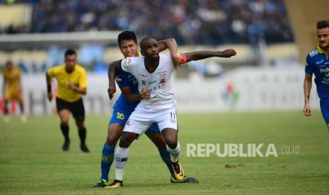 Striker Madura United Greg Nwokolo dibayangi bek Persib Bandung Achmad Jufriyanto pada pertandingan Shopee Liga 1 antara Persib Bandung melawan Madura United di Stadion si Jalak Harupat Soreang, Kabupaten Bandung, Ahad (23/6).