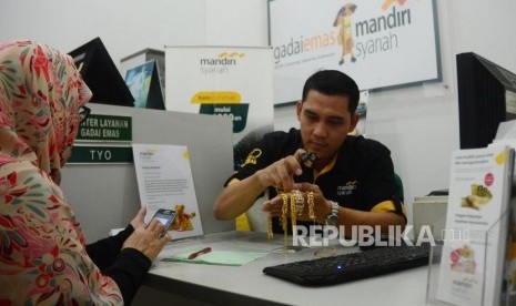 Seorang officer gadai emas Bank Syariah Mandiri (BSM) sedang memberikan penjelasan mengenai produk Gadai Emas Mandiri Syariah kepada seorang nasabah yang akan menggadaikan emasnya di kantor layanan gadai emas BSM di Jakarta, Jumat (9/2).