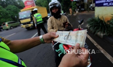 Petugas gabungan melakukan penertiban pajak kendaraan bermotor saat razia pengesahan Surat Tanda Nomor Kendaraan (STNK) di Jalan Raya Kalibata, Jakarta Selatan, Selasa (24/4).