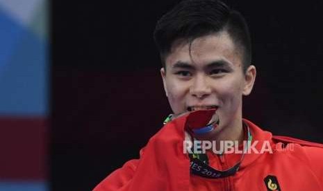 Atlet Wushu Indonesia Edgar Xavier Marvelo  Menggigit medali  usai  prosesi penyerahan medali cabang olahraga Wushu Changquan Putra di Hall B, JIE Expo Kemayoran, Jakarta, Ahad (19/8).