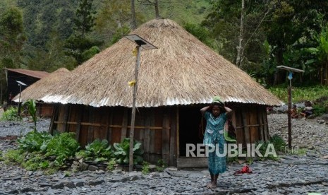 Warga beraktivitas di dekat rumah adat honai yang telah terpasang  jaringan Lampu Tenaga Surya Hemat Energi (LTSHE ) di Kabupaten Puncak Jaya, Papua, Jumat (15/3).