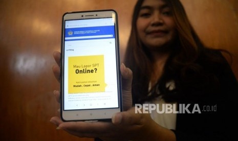 Seorang wajib pajak menunjukan informasi mengenai pengisian SPT secara online di Jakarta, Jumat (9/3).