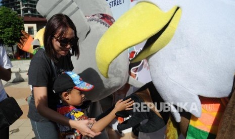 Seorang anak bersalaman dengan maskot Asian Paragames Momo   dikawasan hari bebas berkendara / Car Free Day di Bundaran HI, Jakarta, Ahad (1/4).