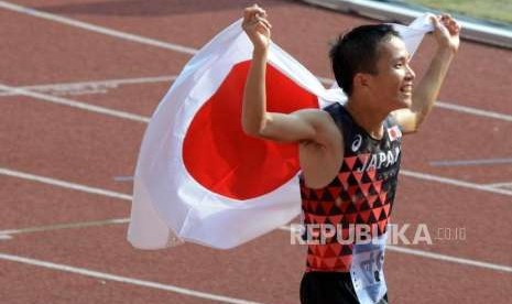 Atlet lari asal Jepang Hiroto Inoue membawa bendera Jepang saat selebrasi kemenangannya pada cabang olahraga atletik nomor maraton putra di Stadion Utama Gelora Bung Karno (SUGBK), Jakarta, Sabtu (25/8).