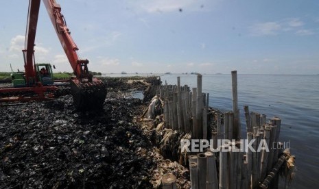 Petugas saat membersihkan sampah yang menumpuk menggunakan alat berat di Muara Angke, Jakarta Utara Senin (19/3).