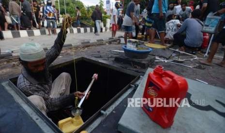 Warga mengambil BBM dari tangki penyimpanan bahan bakar di SPBU, Palu, Sulawesi Tengah, Ahad (30/9).