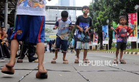 Anak-anak bermain egrang batok kelapa saat car free day di Jalan Jenderal Sudirman, Setiabudi, Jakarta, Ahad (28/1).