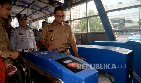 Gubernur DKI Jakarta Anies Baswedan melakukan Tapping (menempelkan) tiket ketika hendak menaiki bus Transjakarta di Halte Dukuh Atas, Jakarta, Selasa (17/10).