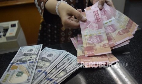 Petugas menghitung mata uang rupiah dan dolar AS di salah satu tempat penukaran uang di Jakarta, Jumat (9/11).