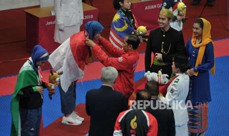 Presiden Joko Widodo memberikan medali emas kepada atlet taekwondo putri Indonesia Defia Rosmaniar saat penyerahan prosesi medali cabang taekwondo nomor poomsae Asian Games 2018 di Jakarta Convention Center, Senayan, Jakarta, Ahad (19/8).