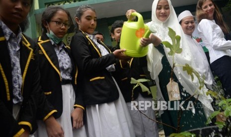 Coorporate Sekretary BNI Syariah Rima Dwi Permatasari (berjilbab) bersama para siswa SMPN 19 Jakarta menyiram tanaman pada kegiatan program Hasanah Earth Day bertajuk we take our earth seriously di SMPN 19 Jakarta, Kamis (19/4).  