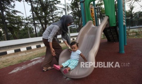 Seorang anak bermain didampingi orang tuanya di area Taman Anak Lapangan Banteng, Jakarta, Kamis (12/7).