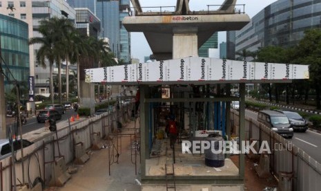 Pekerja menyelesaikan pembangunan halte Transjakarta di bawah pembangunan proyek LRT, Jalan Rasuna Said, Jakarta, Senin (16/7).