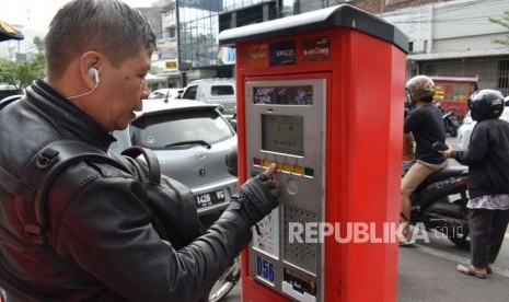 Seorang pemilik kendaraan menggunakan mesin parkir non tunai, di Jalan Jenderal Sudirman, Kota Bandung, Senin (2/7).