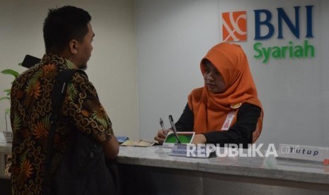 Karyawan melayani transaksi nasabah di kantor layanan BNI Syariah, Jakarta, Senin (5/11).