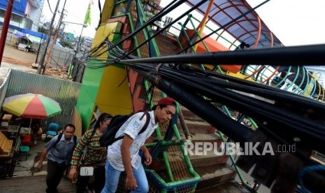 Warga berjalan menghindari instalasi kabel yang melintang di Jembatang Penyeberangan Orang (JPO) Margonda, Depok, Jawa Barat, Selasa (23/10).