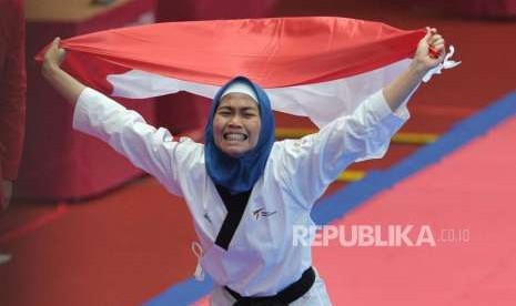 Atlet taekwondo putri Indonesia Defia Rosmaniar melakukan selebrasi seusai meraih medali emas dalam cabang taekwondo nomor poomsae Asian Games 2018 di Jakarta Convention Center, Senayan, Jakarta, Ahad (19/8).