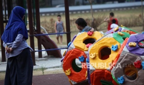 Seorang anak bermain didampingi orang tuanya di area Taman Anak Lapangan Banteng, Jakarta, Kamis (12/7).