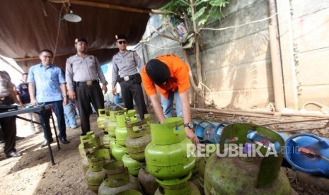 Tersangka menunjukan cara pengoplosan gas saat rilis pengungkapan pabrik pengoplosan tabung gas 3 kilogram ke tabung 12 kilogram dan 50 kilogram di Kawasan Pinang, Tangerang, Banten, Jumat (12/1).