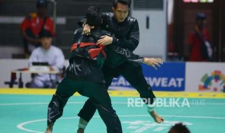 Pesilat Indonesia Komang Harik Adi Putra (pita biru) bertanding melawan Pesilat Singapura Muhammad Shakir Juanda pada babak perempat final cabang pencak silat putra kelas E 65-70 kg Asian Games 2018 di Padepokan Pencak Silat TMII, Jakarta, Jumat (24/8).