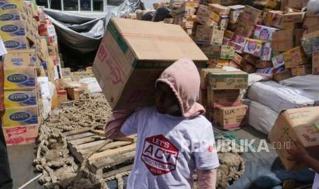 Relawan ACT bersama buruh kapal  bersama-sama mengeluarkan bantuan kemanusiaan dari kapal Kemanusiaaan ACT di Pelabuhan Pantoloan, Palu, Sulawesi Tengah, Sabtu (13/10).