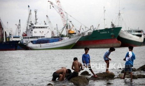 Seorang anak bermain dipesisir laut di Kawasan Muara Baru, Jakarta, Kamis (28/12).