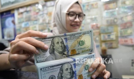 Cadangan Devisa Susut. Pegawai menghitung mata uang dolar AS di jasa penukaran mata uang, Jakarta, Ahad (8/4).