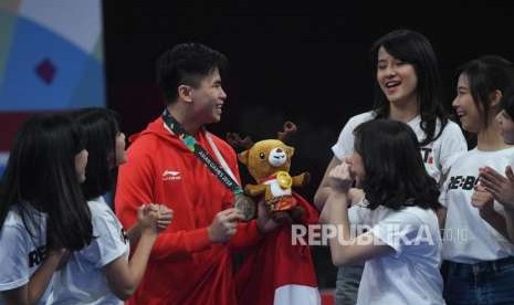 Atlet Wushu Indonesia Edgar Xavier Marvelo menerima ucapan terima kasih dari member JKT 48 usai  prosesi penyerahan medali cabang olahraga Wushu Changquan Putra di Hall B, JIE Expo Kemayoran, Jakarta, Ahad (19/8).