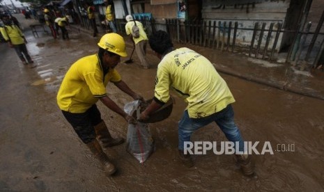 Petugas Bina Marga mengangkut lumpur pascabanjir di Ruas Jalan Jatinegara Barat, Jakarta, Rabu (7/2).