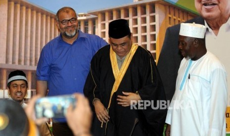 Wakil Ketua Dewan Masjid Indonesia (DMI) yang juga Wakapolri Komisaris Jenderal Pol Syafruddin (kedua kanan) mengenakan baju gamis pemberian Ulama Mekkah Saudi Arabia Syekh Kahlid Al Hamoudi (kiri) di Kantor DMI, Jakarta, Senin (2/4).